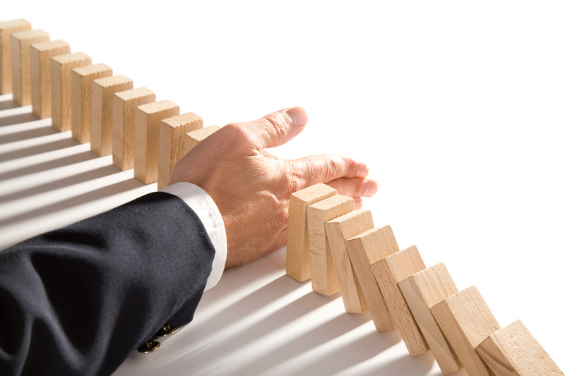 Businessman interrupting wooden dominoes