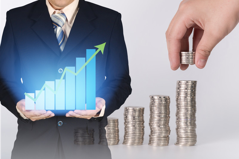 Businessman holding upward graph with coins