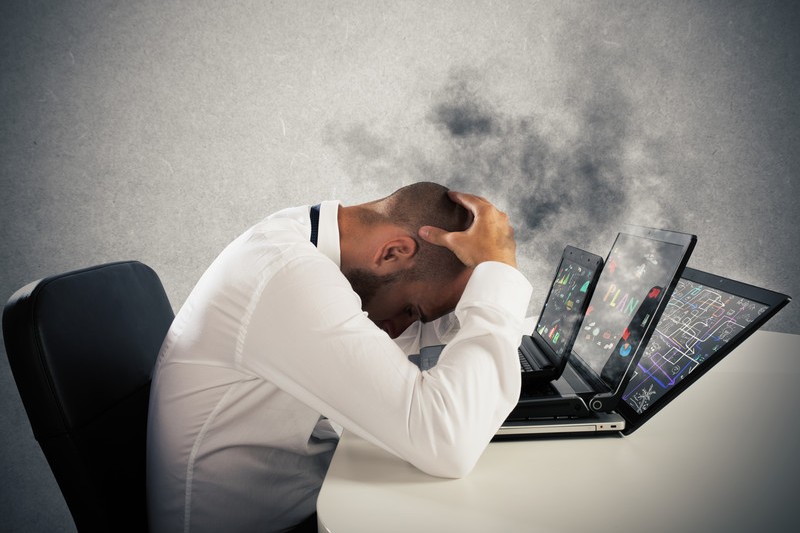 Businessman with head in hands and smoking laptops