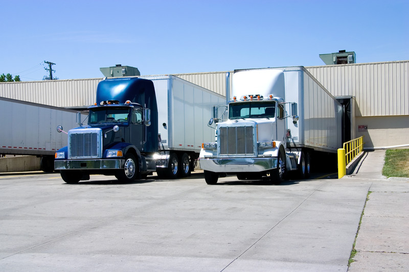 Two semitrucks backed up to a warehouse dock