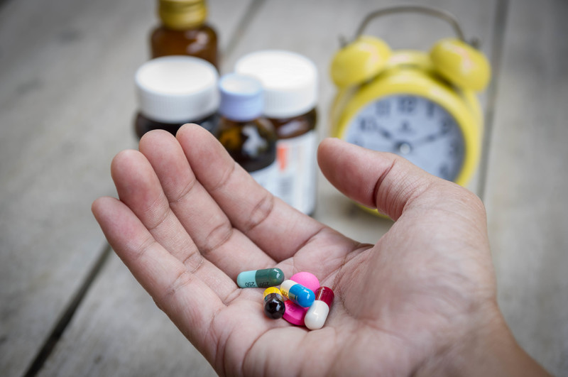 A hand taking a lot of prescription pills