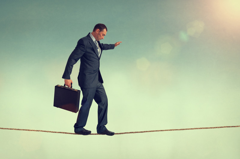 Businessman with a suitcase on a tightrope