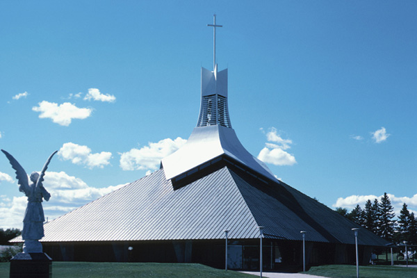 Woman in wedding gown holding bouqet and man in tuxedo in front of church