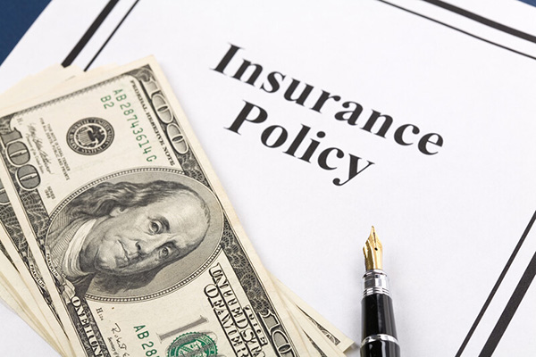 A stack of $100 dollar bills on an insurance policy form