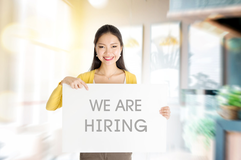 Young woman holding a we are hiring sign
