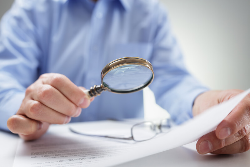 Businessman reading documents with a magnifying glass