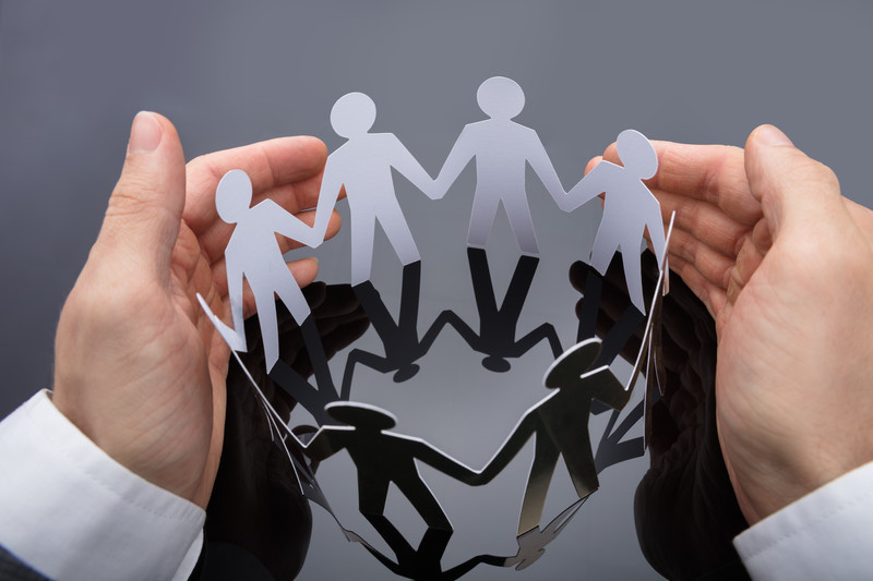 Hands protecting linked paper dolls