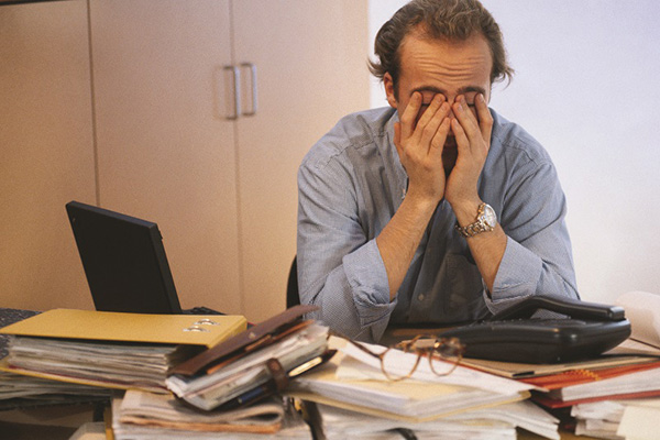 Man behind desk with face in hands