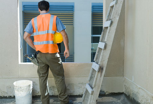 Construction worker looking at window of outside of a house
