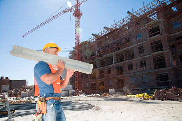 Construction worker carrying a concrete beam