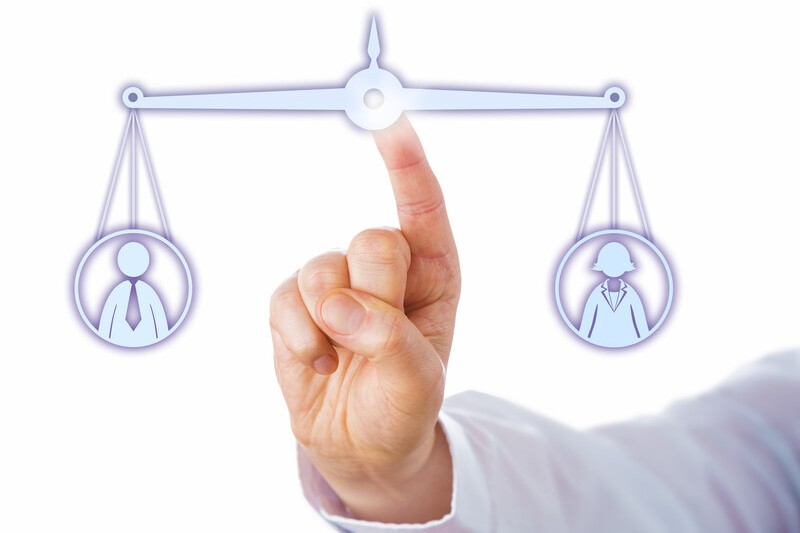 Hand pointing to scale with icon of man on one side and woman on other