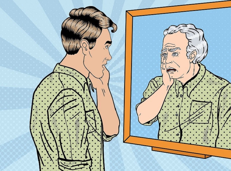 Younger man looking at older version of self in mirror