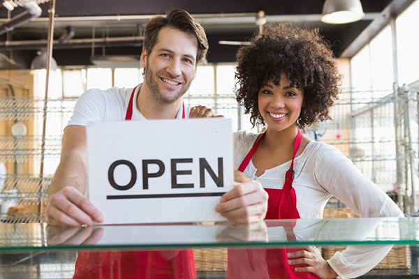 Two coworkers holding an open sign
