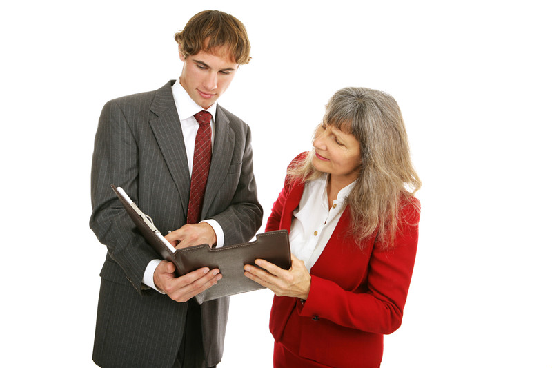 Woman and man in suits looking at binder