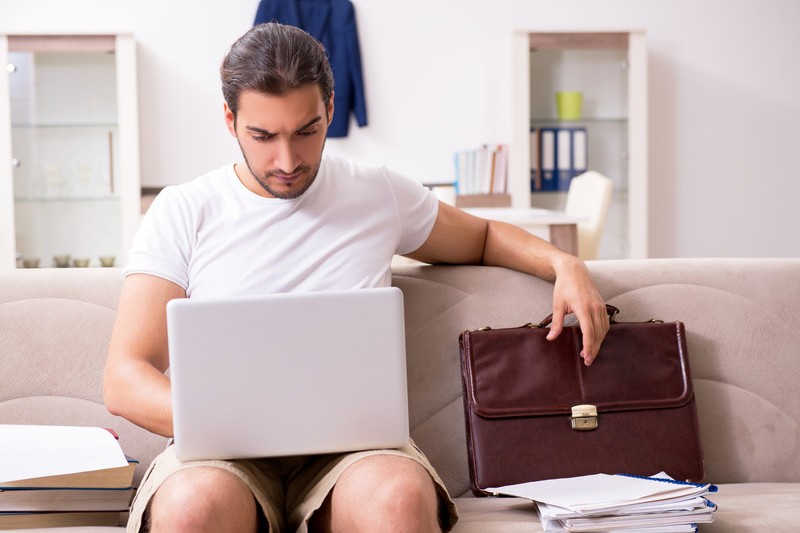 Man teleworking with laptop, briefcase, and papers