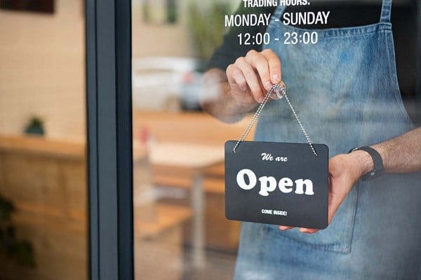 Small Business Person Hanging an Open Sign in The Window