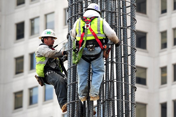 Construction workers harnessed and working on rebar