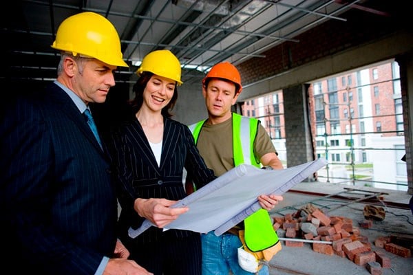 business professionals and construction worker viewing blueprint