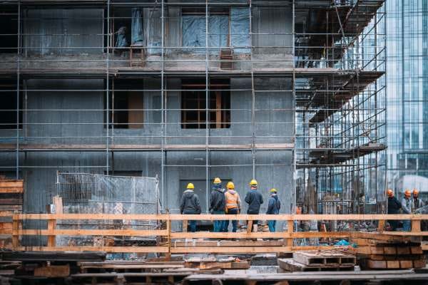 construction workers looking up at a partially constructed building through scaffolding