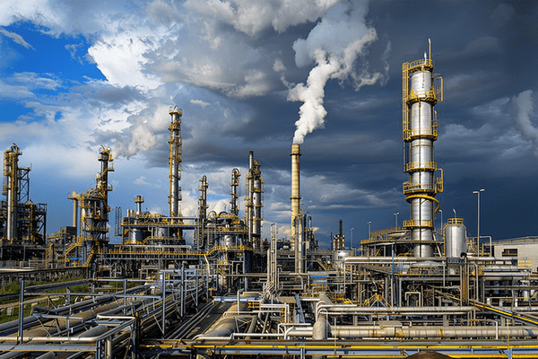 A chemical plant on a sunny day with a large storm brewing in the distance