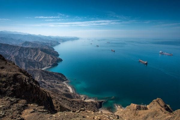 view from land of the Strait of Hormuz and cargo ships on a bright blue sky day