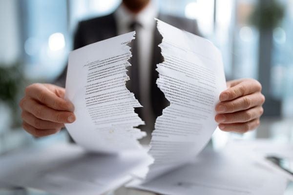 Businessperson holding two halves of a contract torn in half