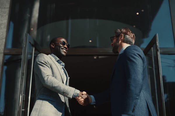 Two businessmen shaking hands in front of an office building
