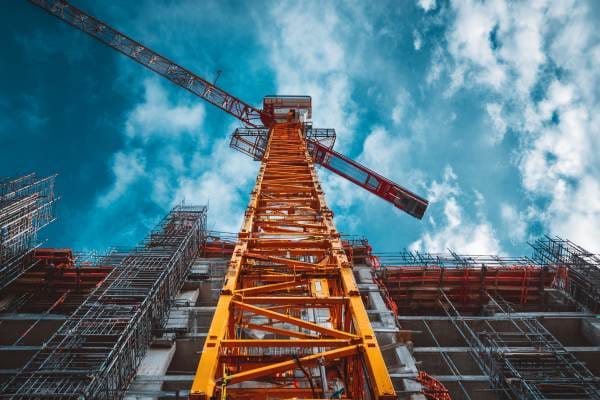 looking up at a tall crane next to a building under construction at a construction site