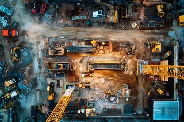 Overhead view of a construction site with yellow cranes and blue buildings