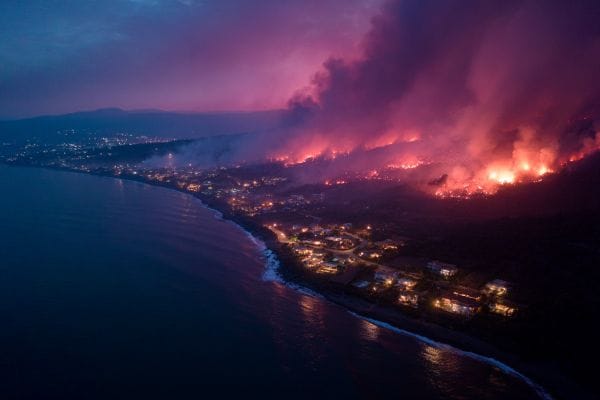 wildfire flames and smoke heading towards a coastal town at night