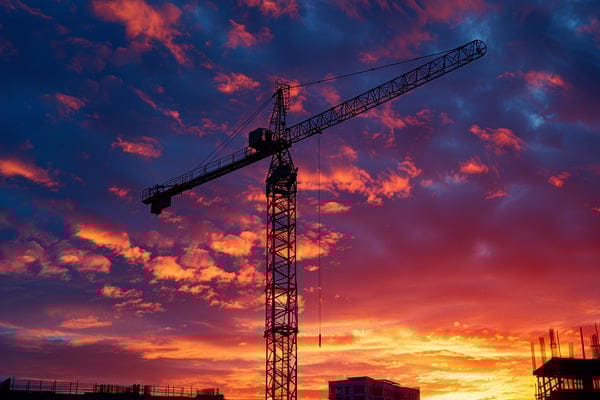 A construction crane in the midst of a construction site at sunset