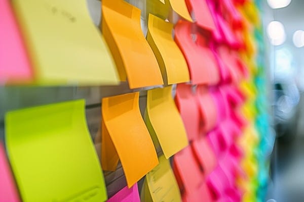Many multi-colored post-it notes placed in lines along an office wal