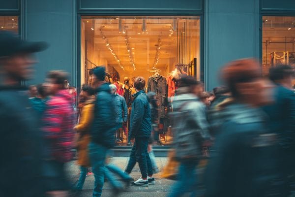 people rushing by a storefront