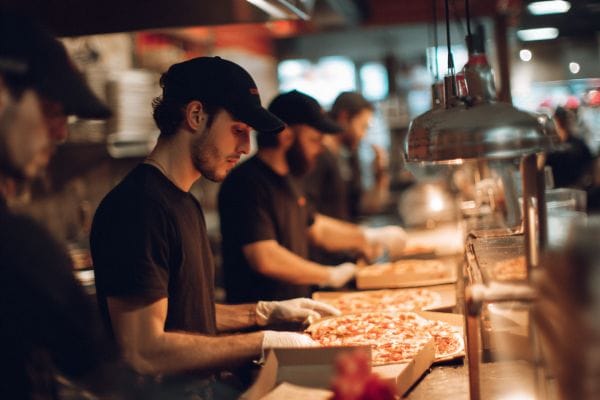 pizza parlor staff boxing pizzas to go under heat lamps