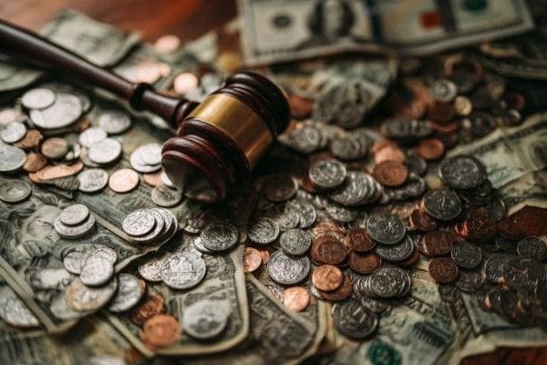 A wooden gavel on top of a pile of coins and paper
                    money