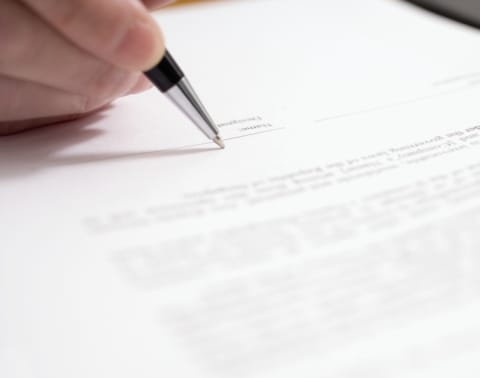 A hand signing a document